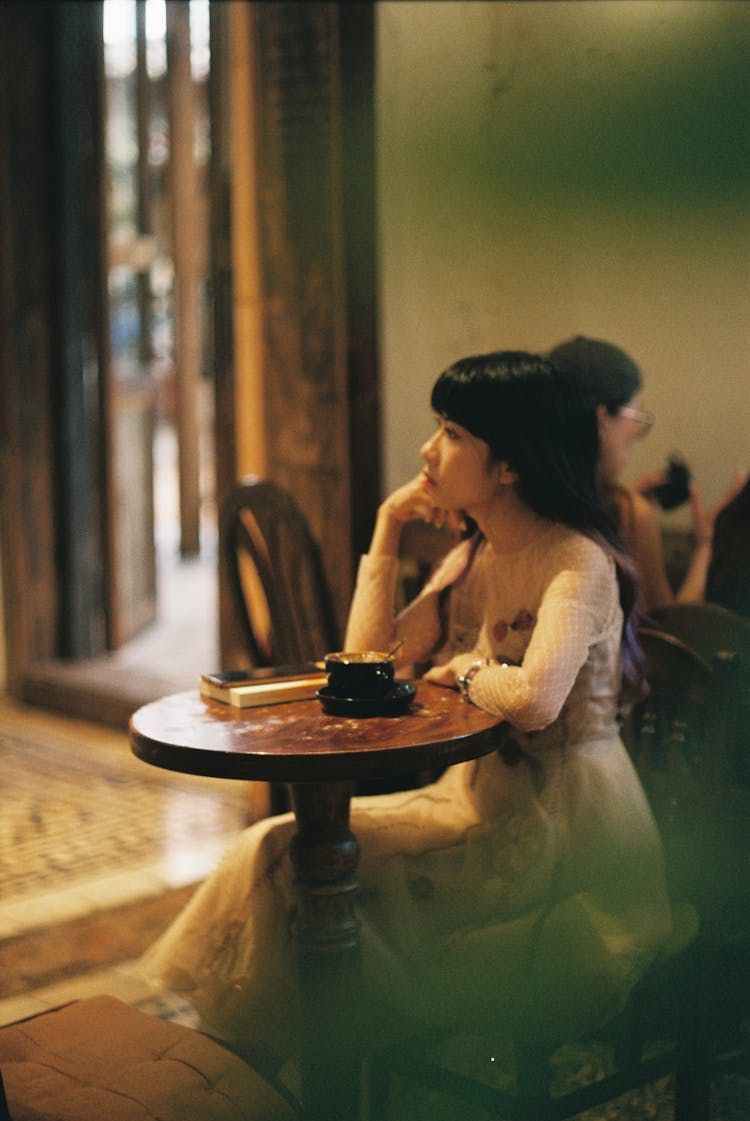 Young Woman Sitting At The Table In A Cafe