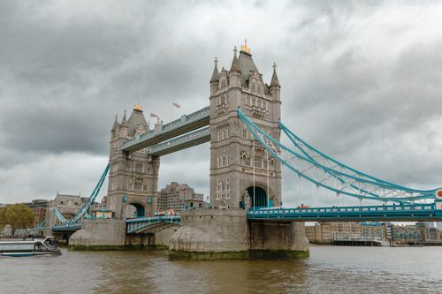 Free View of the Tower Bridge in London on a cloudy day, showcasing its iconic design and urban setting. Stock Photo