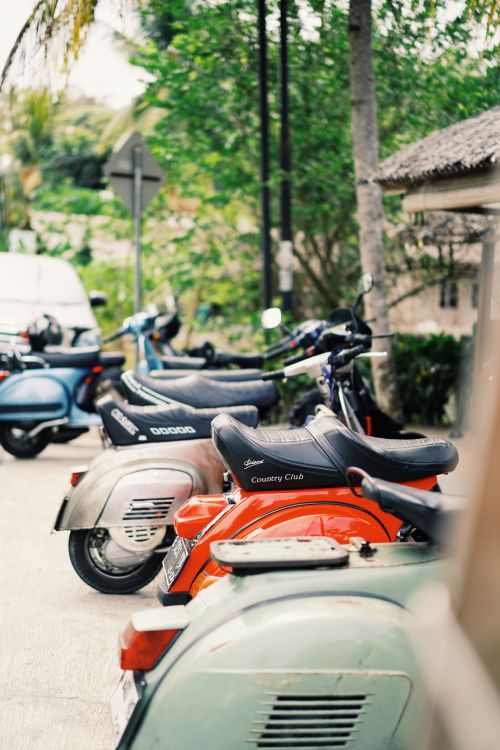 Free Vibrant motor scooters aligned on an urban street under a sunny sky, capturing the essence of city life. Stock Photo