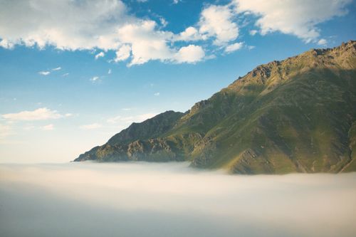 Free High mountain peaks emerging from a sea of fog under a vivid blue sky. Stock Photo