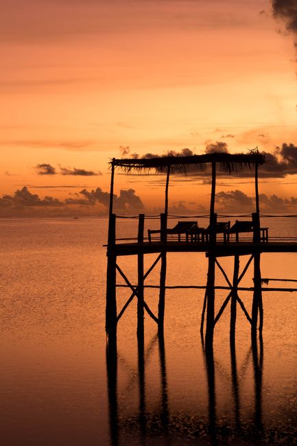 A tranquil silhouette of a pier in Zanzibar during a vibrant sunset over the ocean.