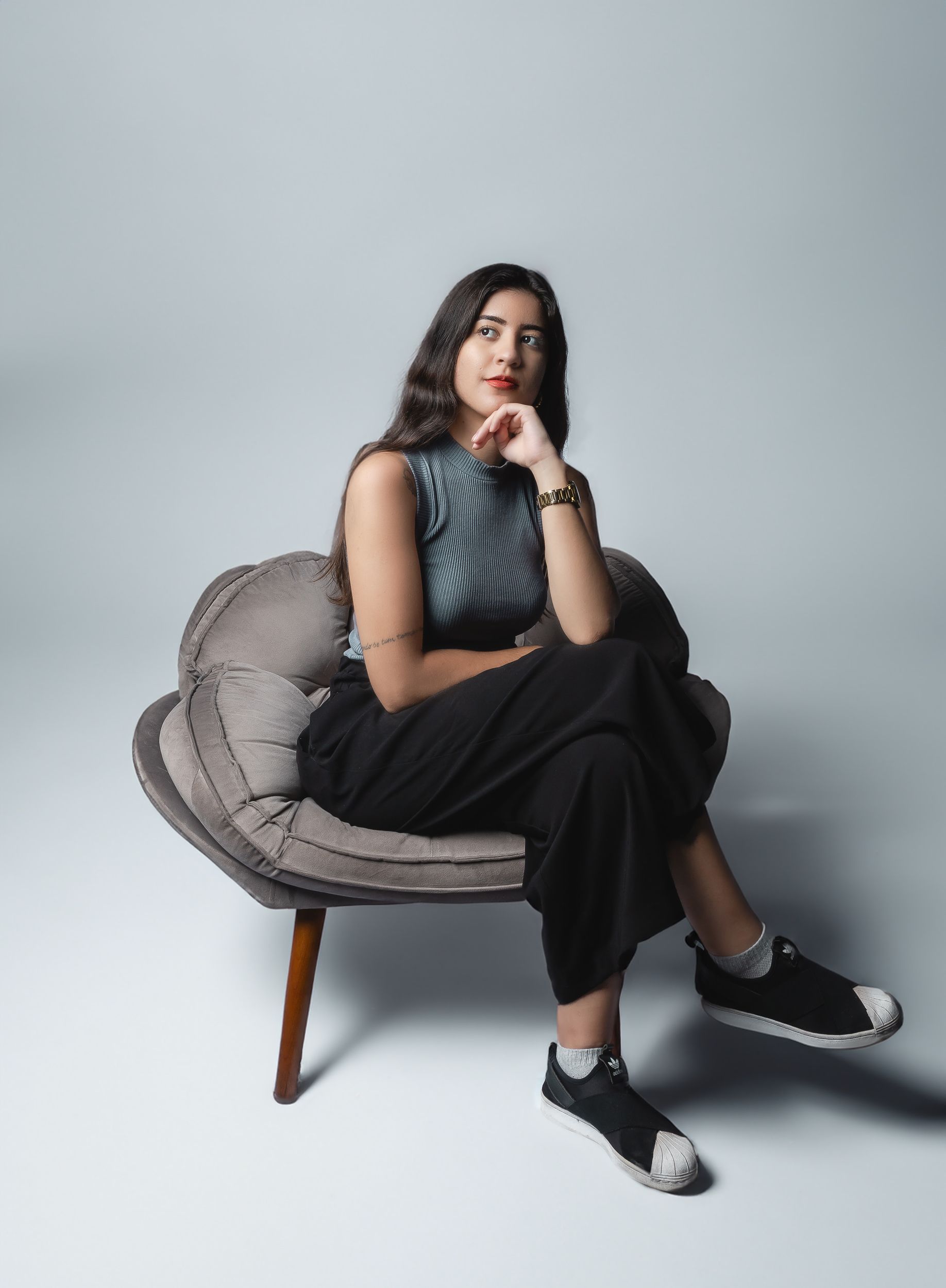 Pensive Model in a Gray Sleeveless Blouse and Black Pants Sitting on an ...
