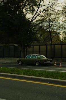 A classic vintage Mercedes car parked on a city street, surrounded by trees.