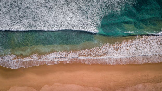 Drone shot of waves crashing on Tarifa beach, Spain, showcasing beautiful shorelines.