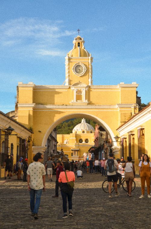 Free Discover the bustling Santa Catalina Arch in Antigua, capturing vibrant street life on a sunny day. Stock Photo
