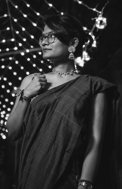 Free A woman wearing a sari poses gracefully at night with sparkling background lights in Kolkata. Stock Photo