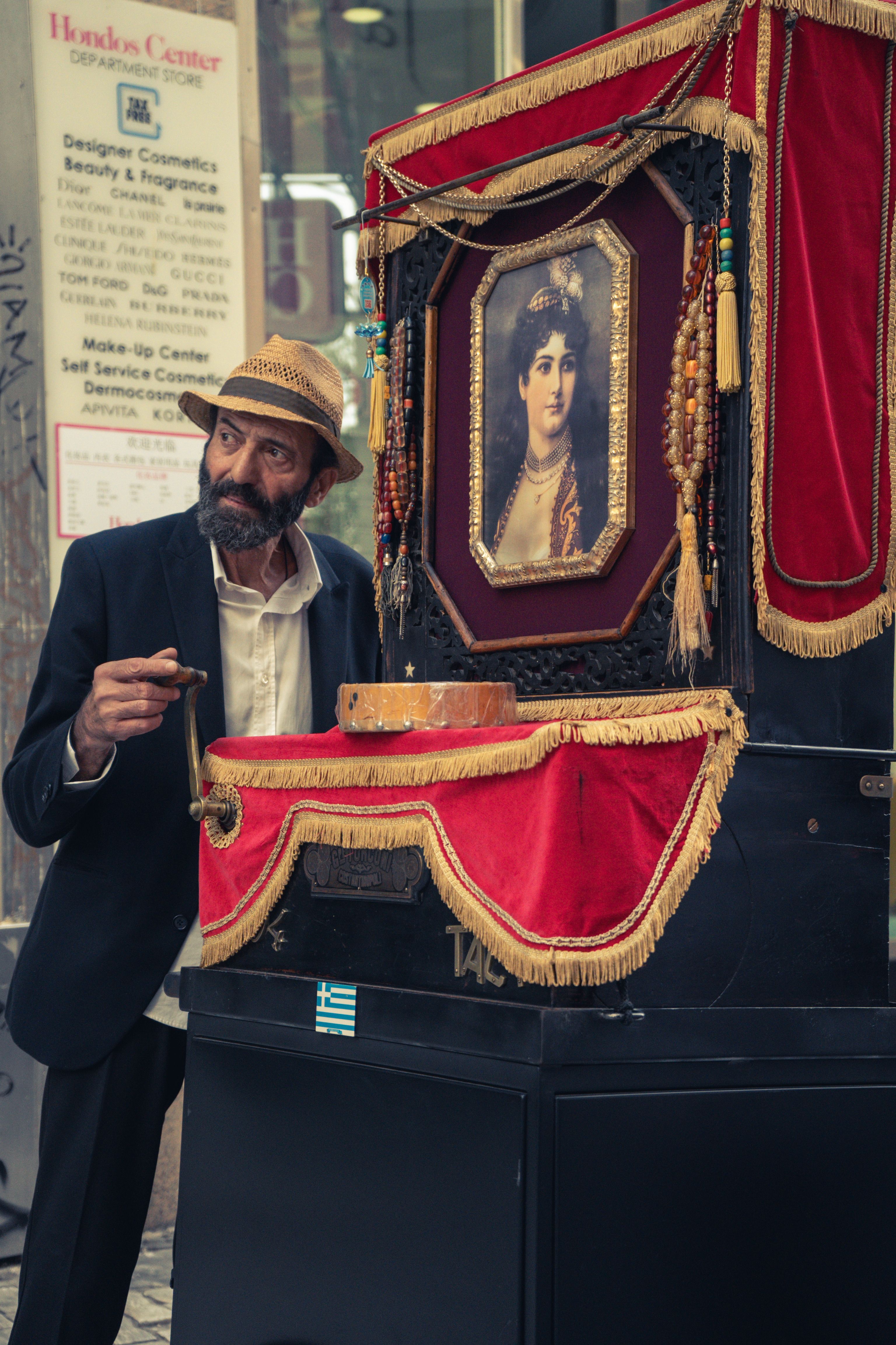 Man in a suit playing a vintage barrel organ on a city street.