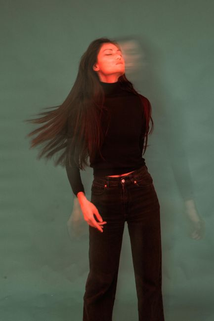 Artistic portrait of a woman with motion blur and long hair against a gray background.