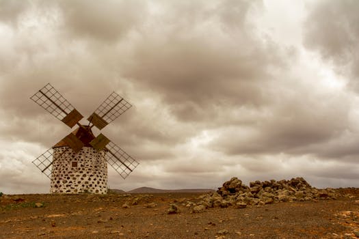Old windmill in a desolate desert under cloudy skies, capturing a vintage feel in Spain.