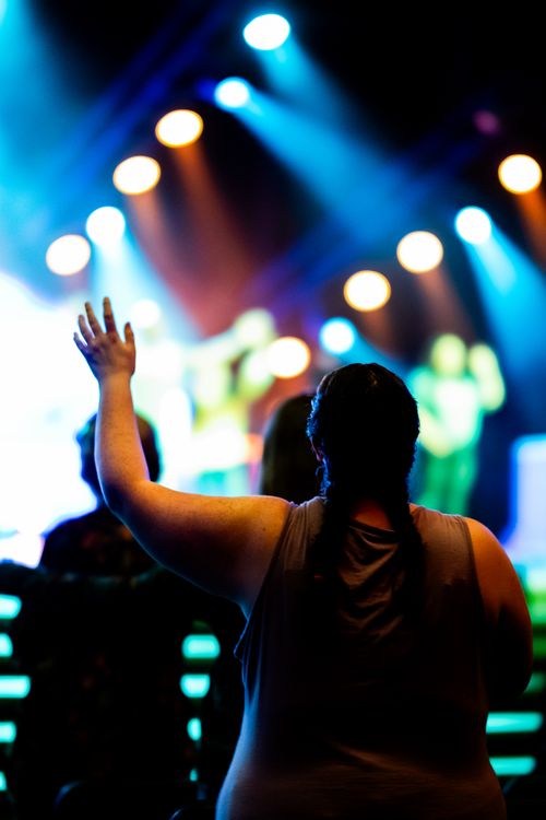 Free A woman enjoys live music at a concert with vibrant stage lighting and a festive atmosphere. Stock Photo
