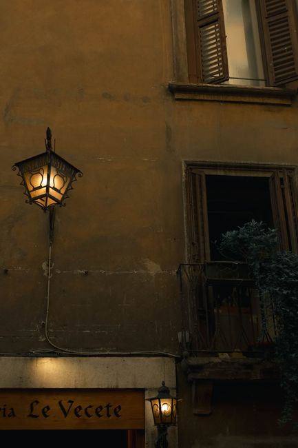 Warm evening glow on a rustic building facade in Verona, Italy with street lamps.