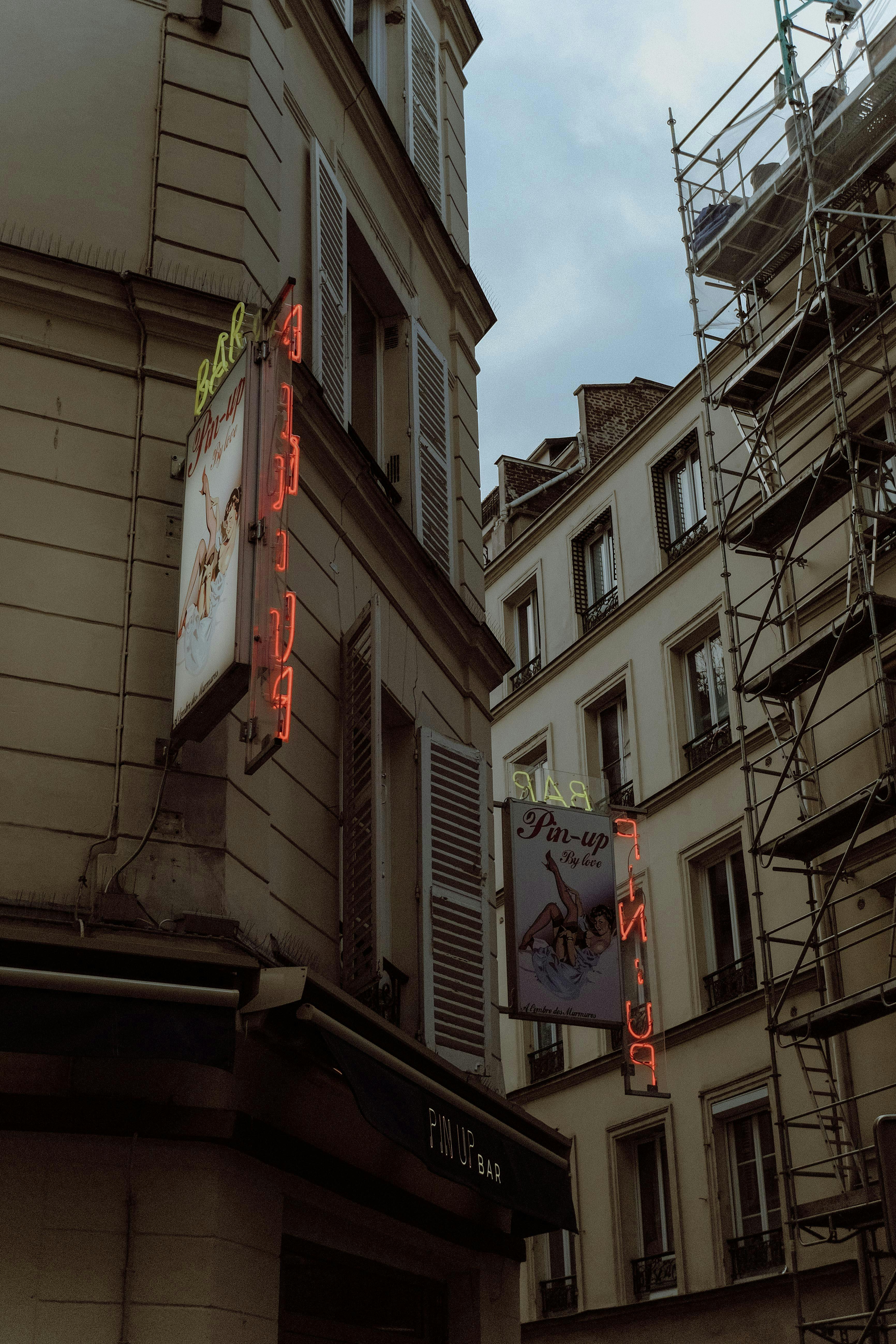 Street view of a corner in Paris with neon signs and traditional architecture.