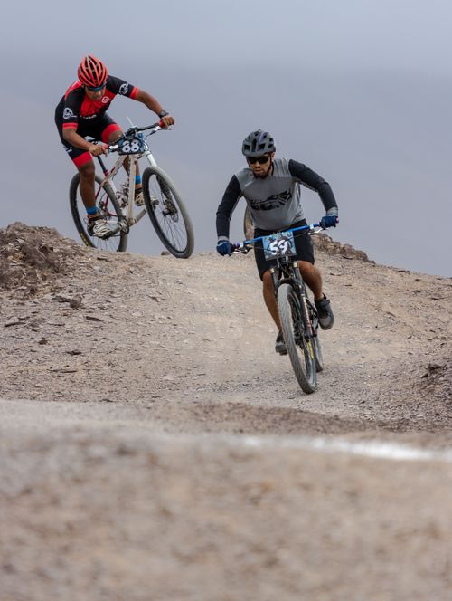 Free Two cyclists compete intensely on a rugged mountain path engaging in a thrilling race. Stock Photo