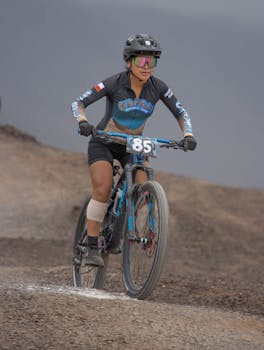 Dynamic portrait of a woman mountain biking on challenging outdoor terrain, showcasing athleticism and determination.