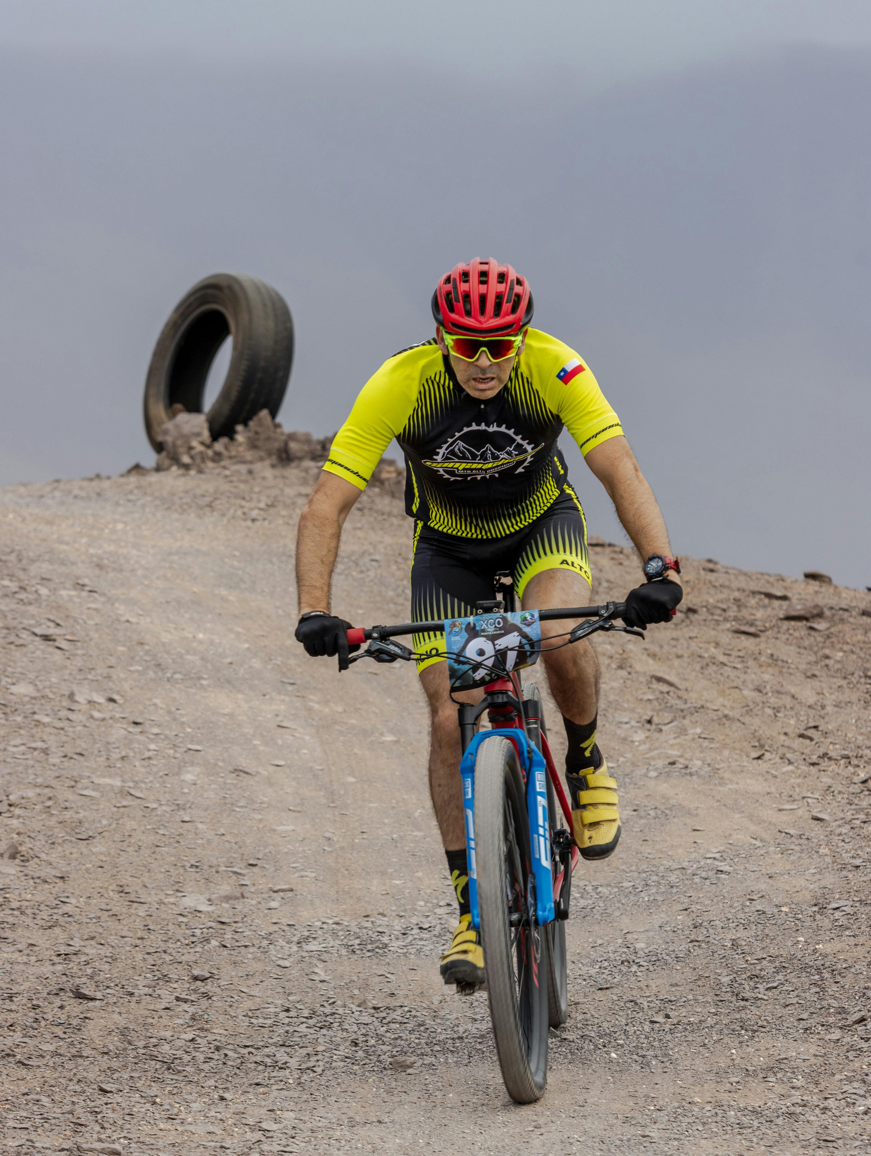 A cyclist in bright gear races on a rugged mountain trail, showcasing endurance and skill.
