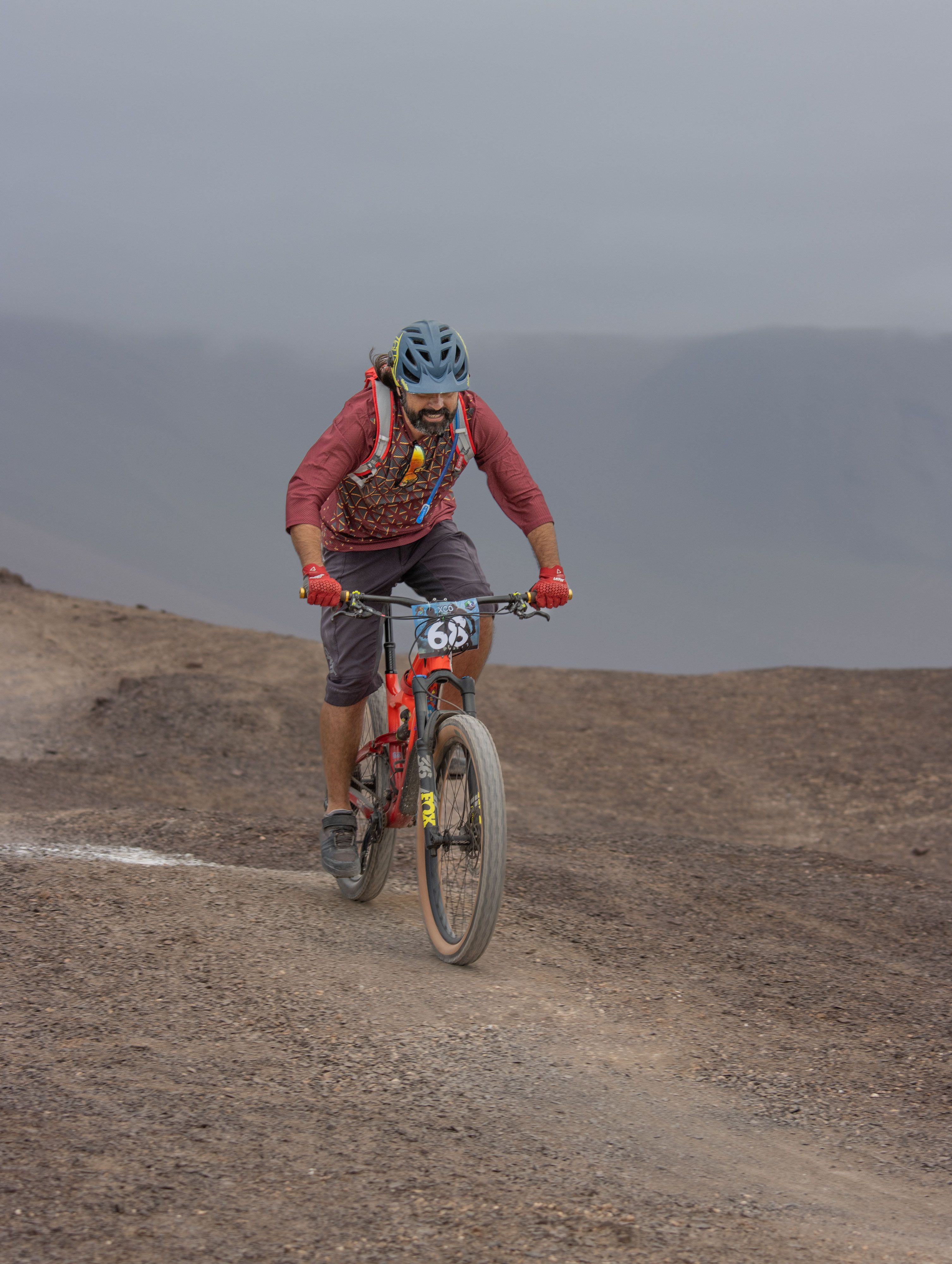 Man mountainbiken op een uitdagend pad te midden van een desolaat landschap, wat avontuur en uithoudingsvermogen laat zien.