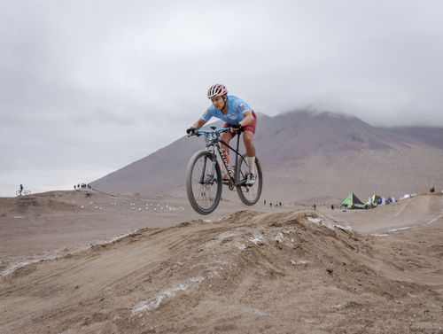 Free A cyclist leaps over a dirt hill in an exciting mountain bike competition. Stock Photo