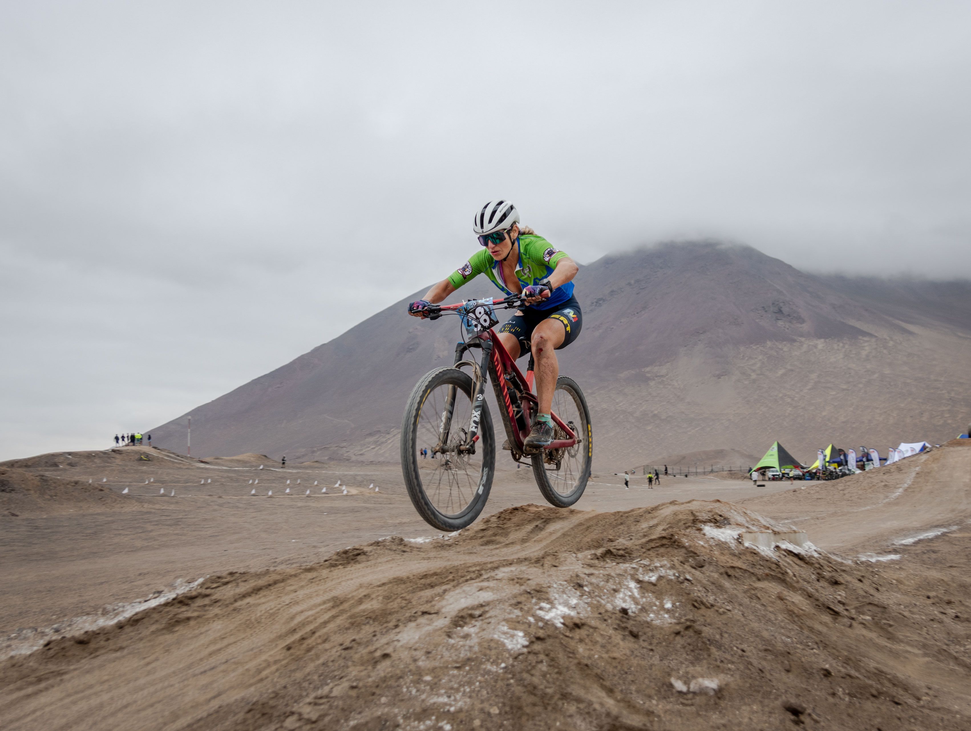 Dynamic shot of a woman cyclist competing on a desert biking trail with mountains in the background.