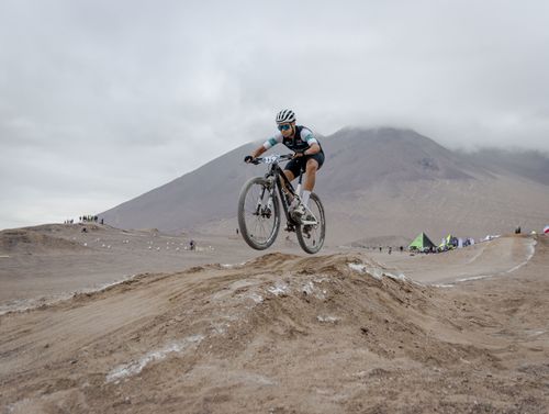 Free Mountain biker jumps over dirt mound in a competitive off-road race. Stock Photo