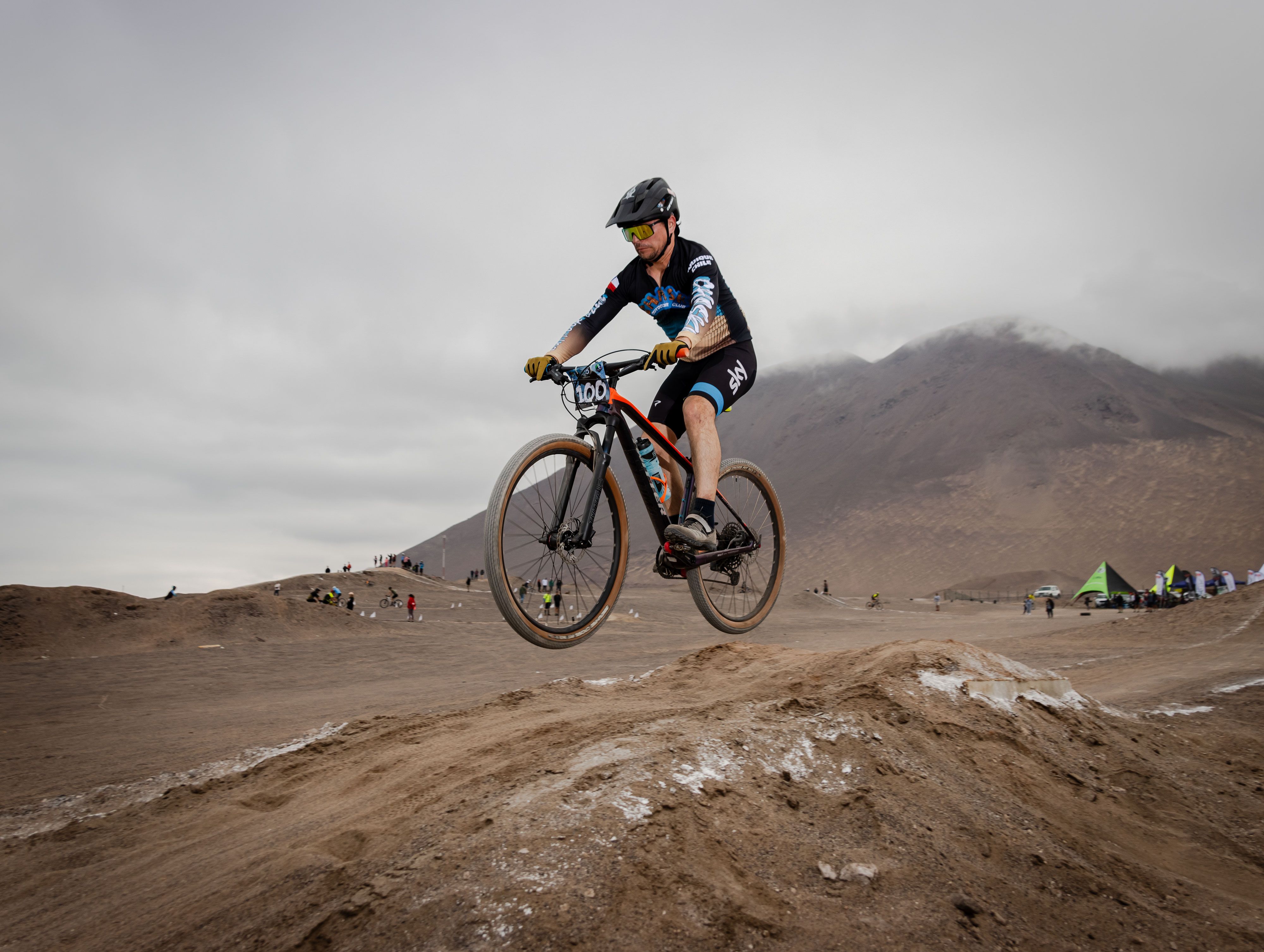 A mountain biker jumps over a trail in a desert race, showcasing skill and adrenaline.