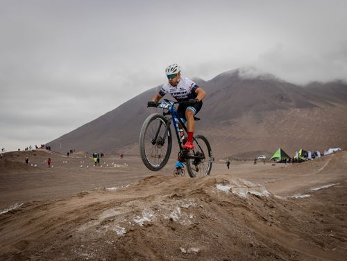 Free A mountain biker in full gear races over rugged desert terrain under cloudy skies. Stock Photo