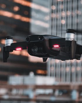 Dynamic close-up of a drone flying against a background of city buildings, highlighting urban technology.