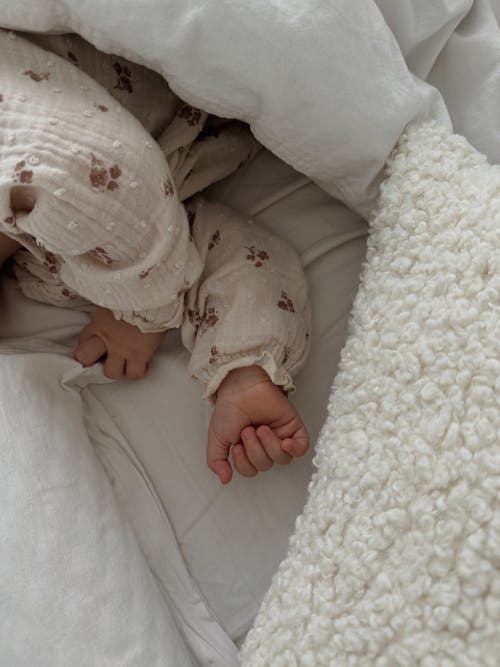 Tiny Hands of a Baby Sleeping in a Bed