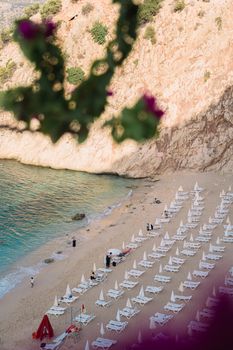 Aerial view of a stunning beach resort with rows of loungers, umbrellas, and clear blue sea.