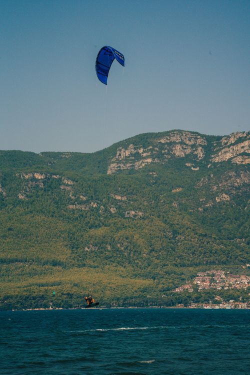 Free A kitesurfer enjoying a summer day on the water with lush hills in the background. Stock Photo