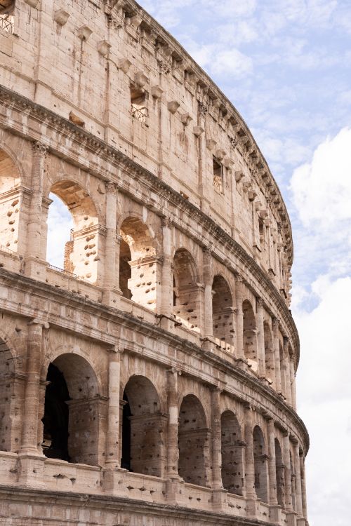 Free An impressive close-up of the ancient Colosseum's arches in Rome against a clear sky. Stock Photo