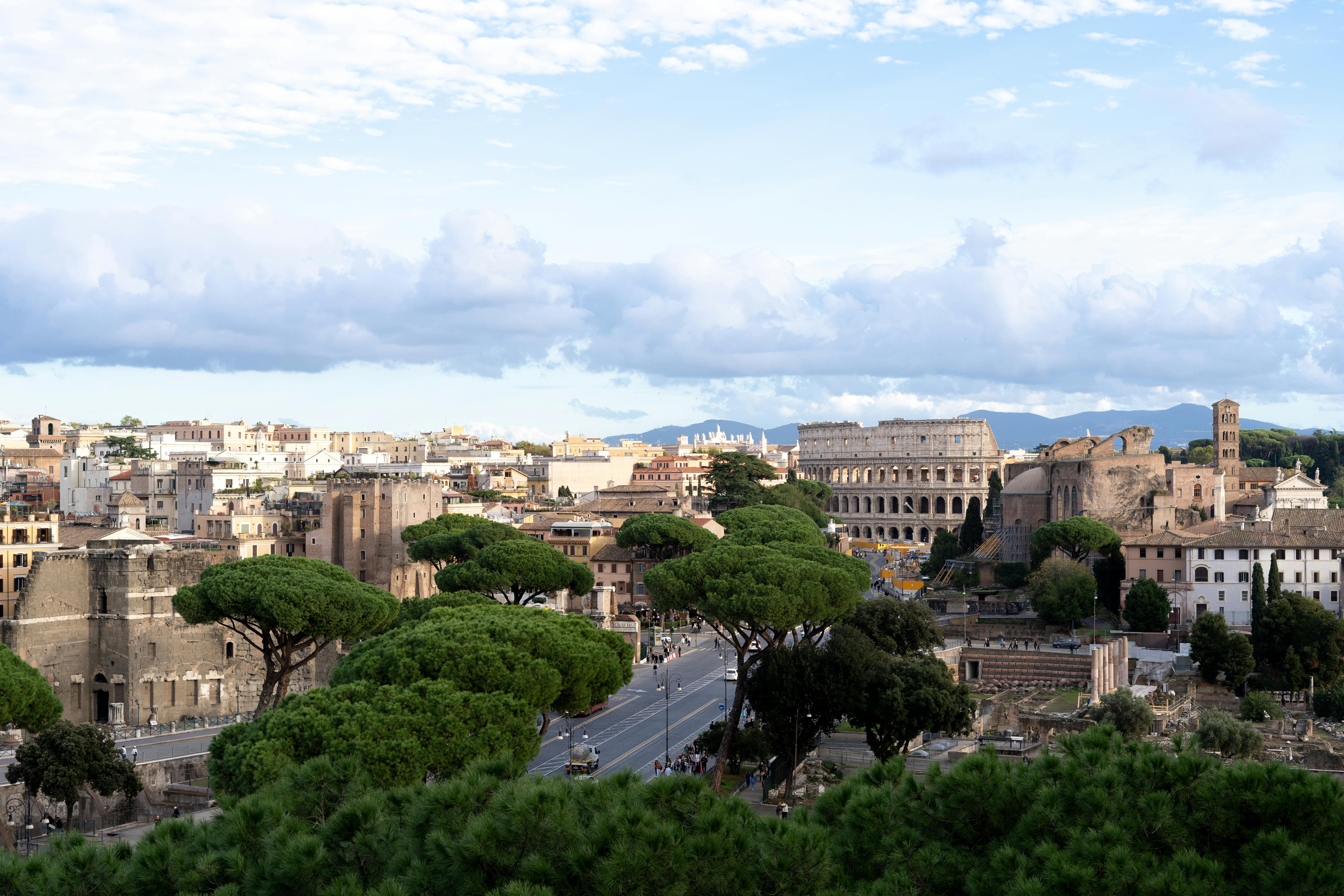 Free Scenic aerial view of Rome showing the iconic Colosseum and historic architecture under a blue sky. Stock Photo