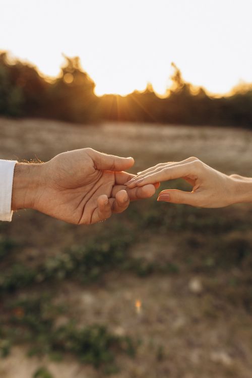 Free A romantic moment captured as a couple holds hands in a sunlit field. Stock Photo
