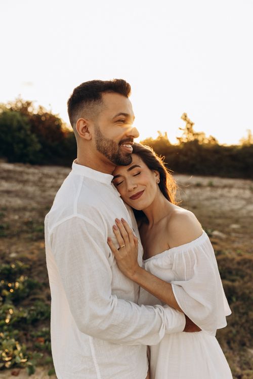 Free A loving couple shares a warm embrace in a sunlit outdoor setting, conveying affection and joy. Stock Photo