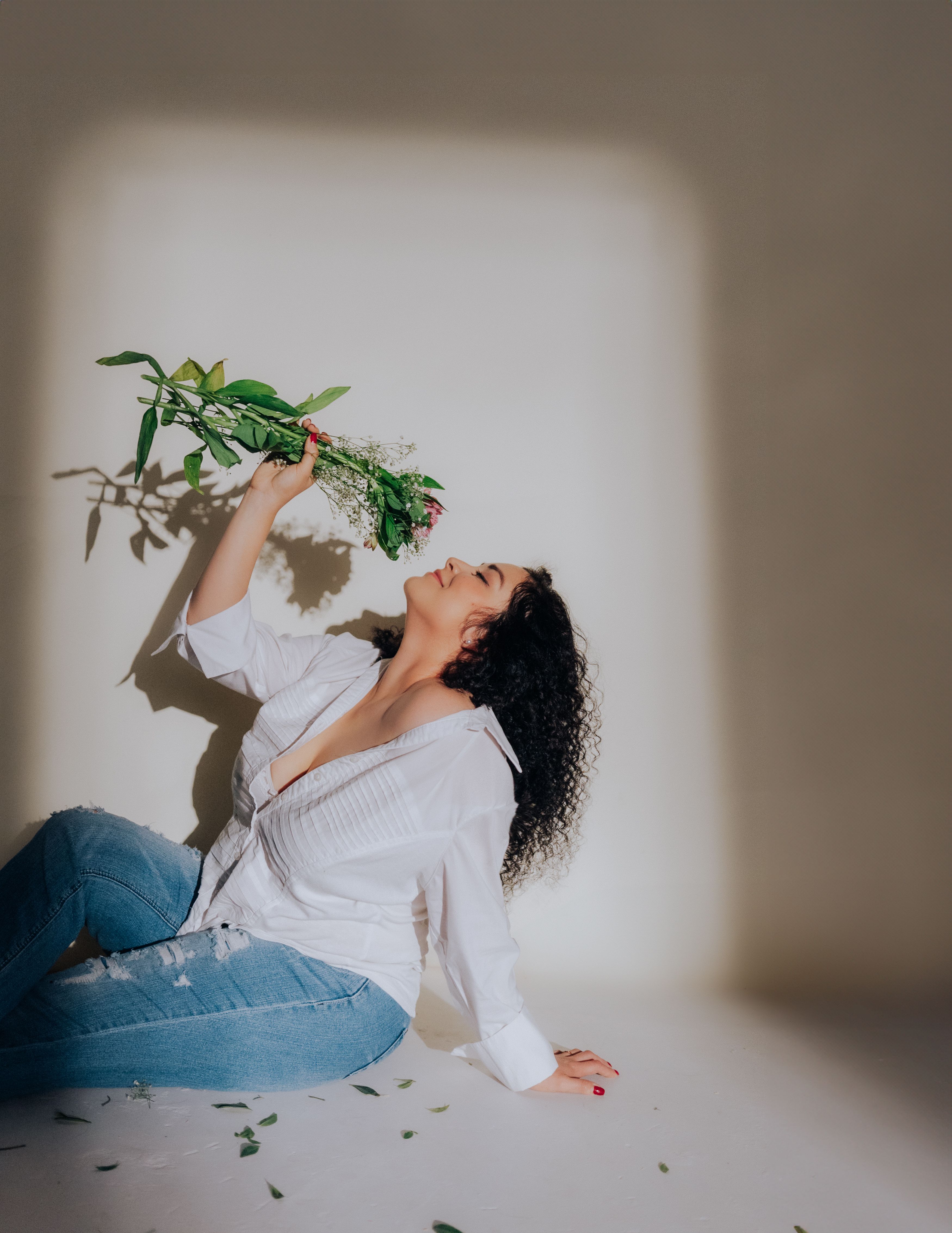 Free A stylish woman enjoys a vibrant bouquet under dramatic lighting, creating an artistic indoor portrait. Stock Photo