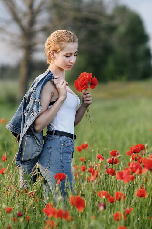 Young Woman Standing on a Meadow with Poppies 