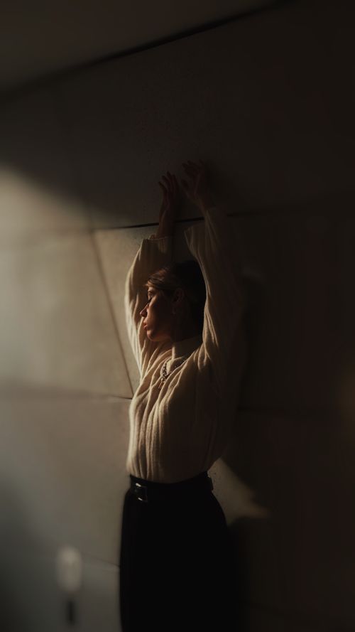 Free Stylish portrait of a woman posing against a wall in soft lighting, exuding elegance and fashion flair. Stock Photo