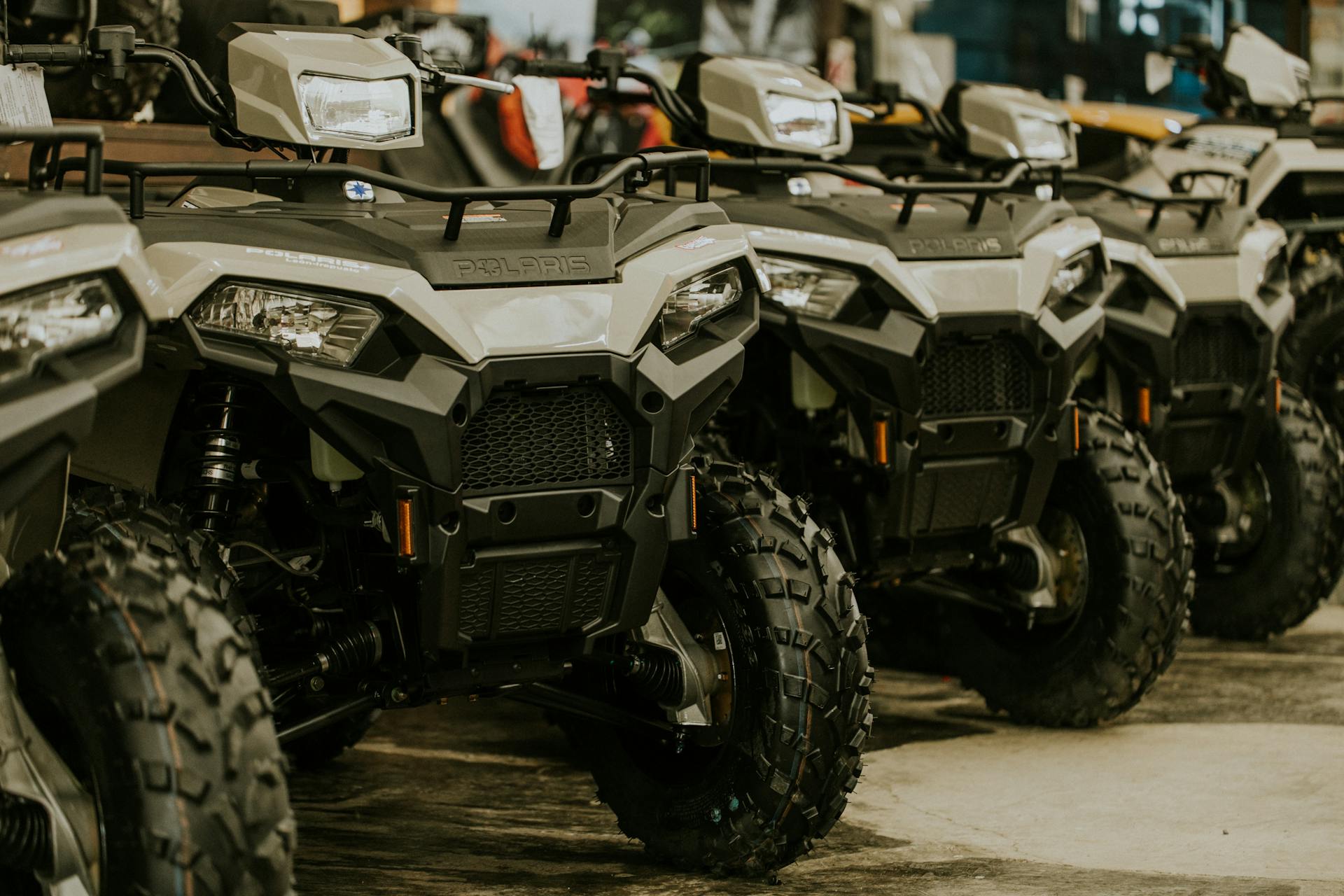 Parked Polaris Sportsman quad bikes lined up in an outdoor setting, showcasing their rugged design.