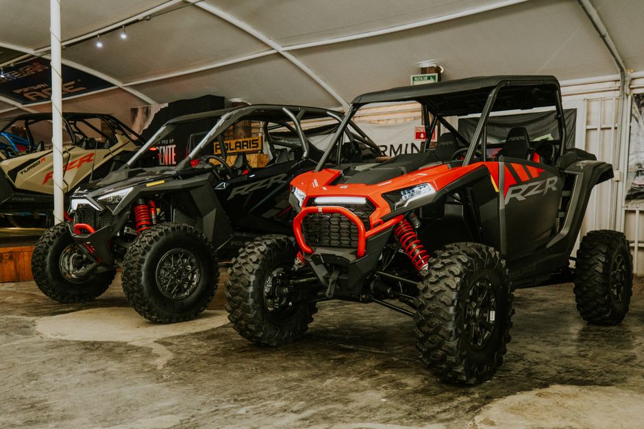 Two rugged offroad buggies parked indoors at a vehicle showcase event, highlighting modern design.