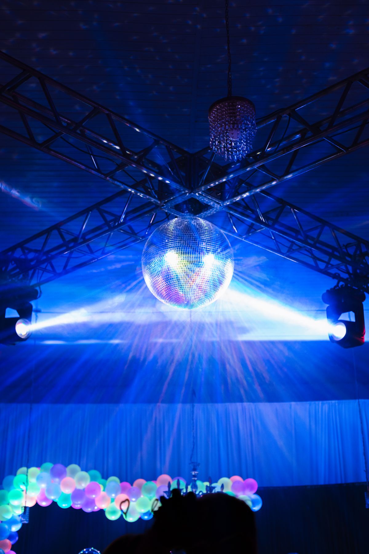 Ballroom truss rig with beams and mirror ball above an event floor