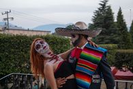 A couple in vibrant traditional costumes celebrating Día de los Muertos in Lerma de Villada, Mexico.
