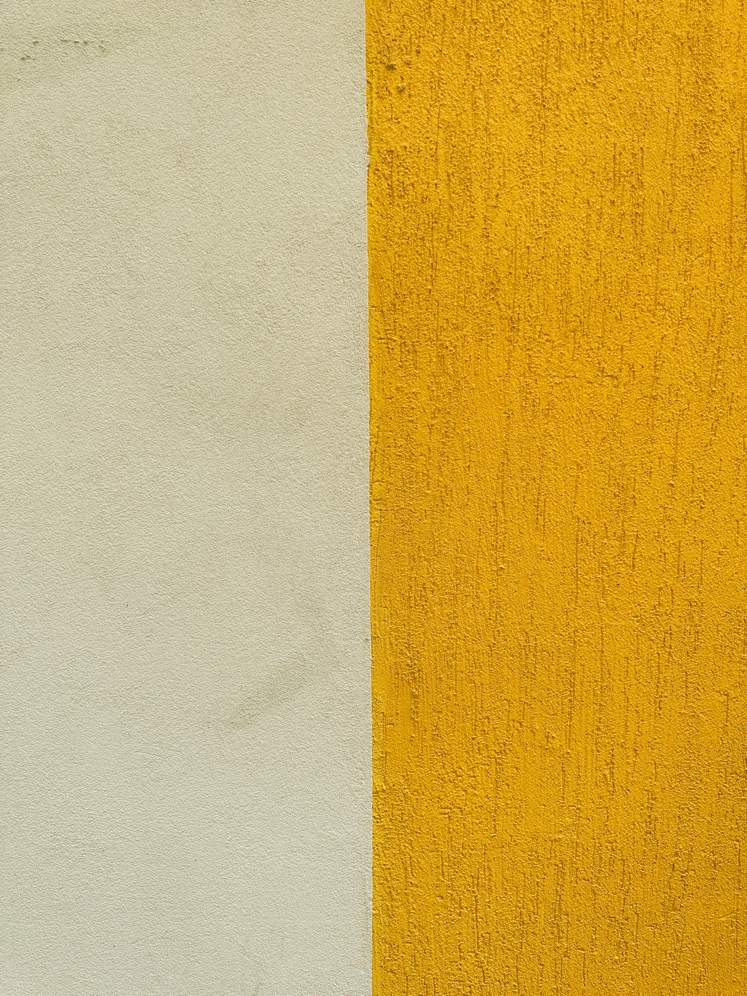Close-up of a textured wall featuring a vertical division with yellow and white sections.