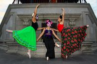 Ballet dancers in colorful costumes celebrate Dia de Muertos with traditional makeup and vibrant skirts.