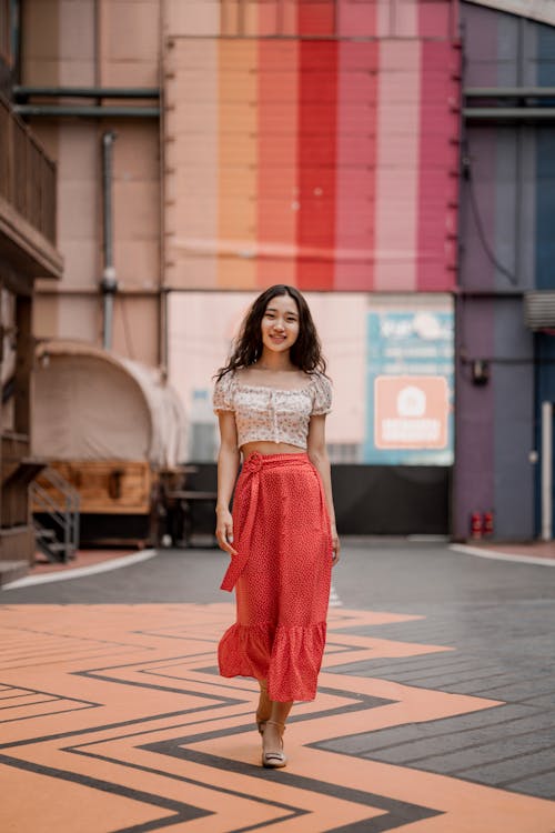 Young Woman in a Long Skirt Walking on the Pavement 