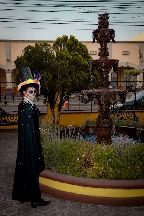 A Man in a Costume for the Day of the Dead Standing by a Fountain