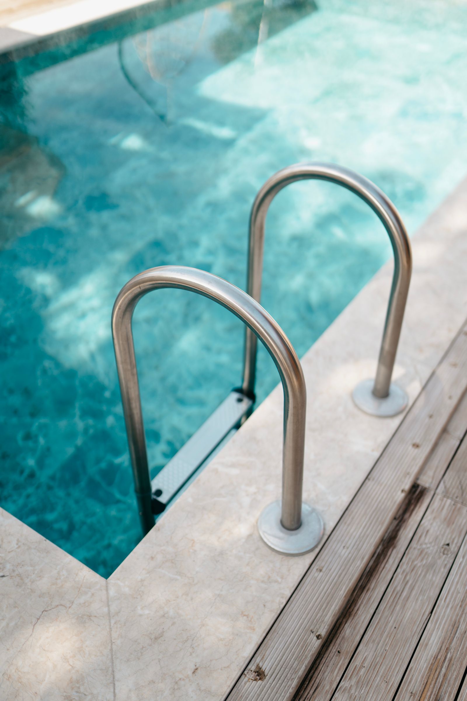 Stainless steel pool ladder in bright blue water