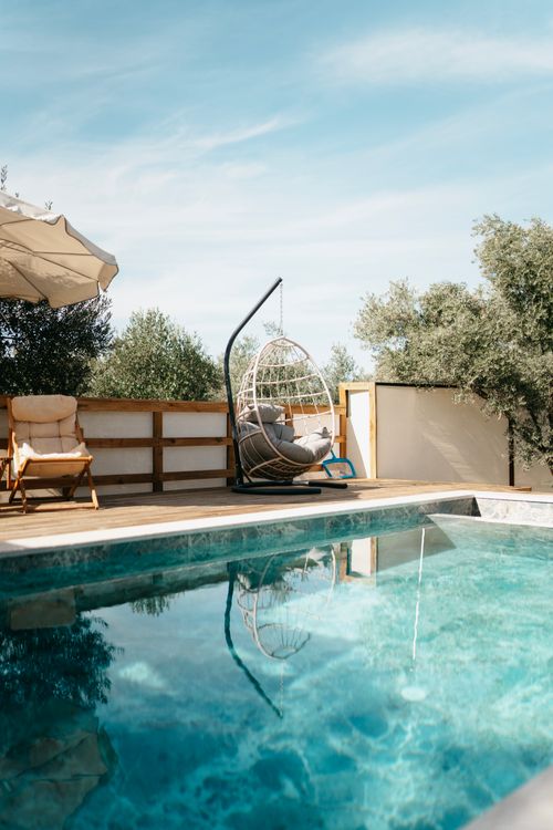 Free Relaxing poolside scene in Ortaca, Türkiye, featuring a swing chair and clear skies. Stock Photo