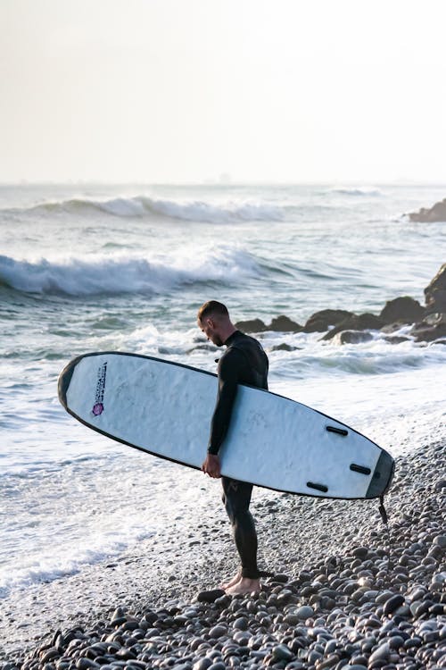 Man with a Surfboard Standing on the Beach 