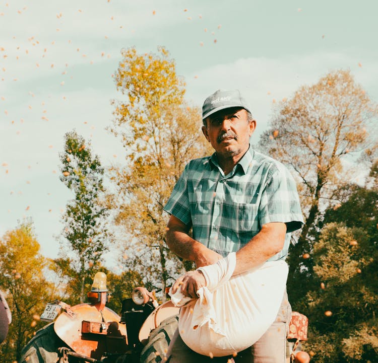 Farmer With A Bag Of Seeds At The Tractor