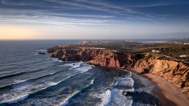 Breathtaking aerial view of the rocky coastline near Aljezur, Portugal at sunset.