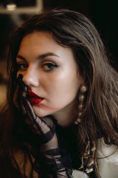 Close-up portrait of a young woman with red lipstick and elegant style, wearing gloves.